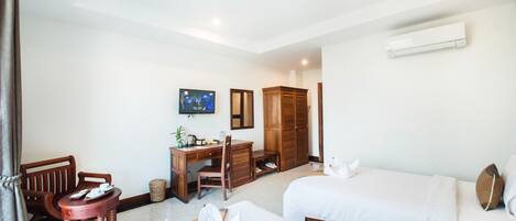 A hotel room with two beds, a desk with a chair, a television, and a wardrobe.