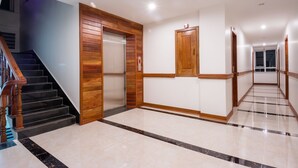 A modern interior with a wooden staircase, a lift, and a hallway with a tiled floor. - Relax Hotel (Phnom Penh)