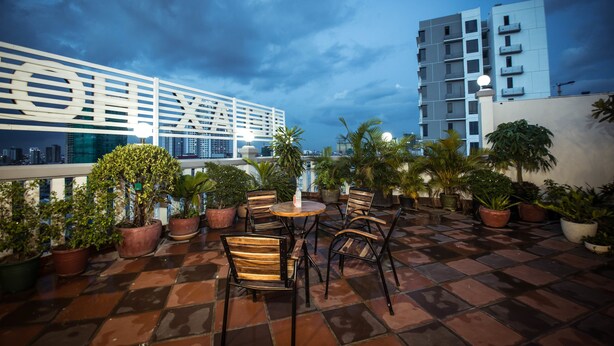 A rooftop terrace with potted plants, a round table, and chairs. - Relax Hotel (Phnom Penh)