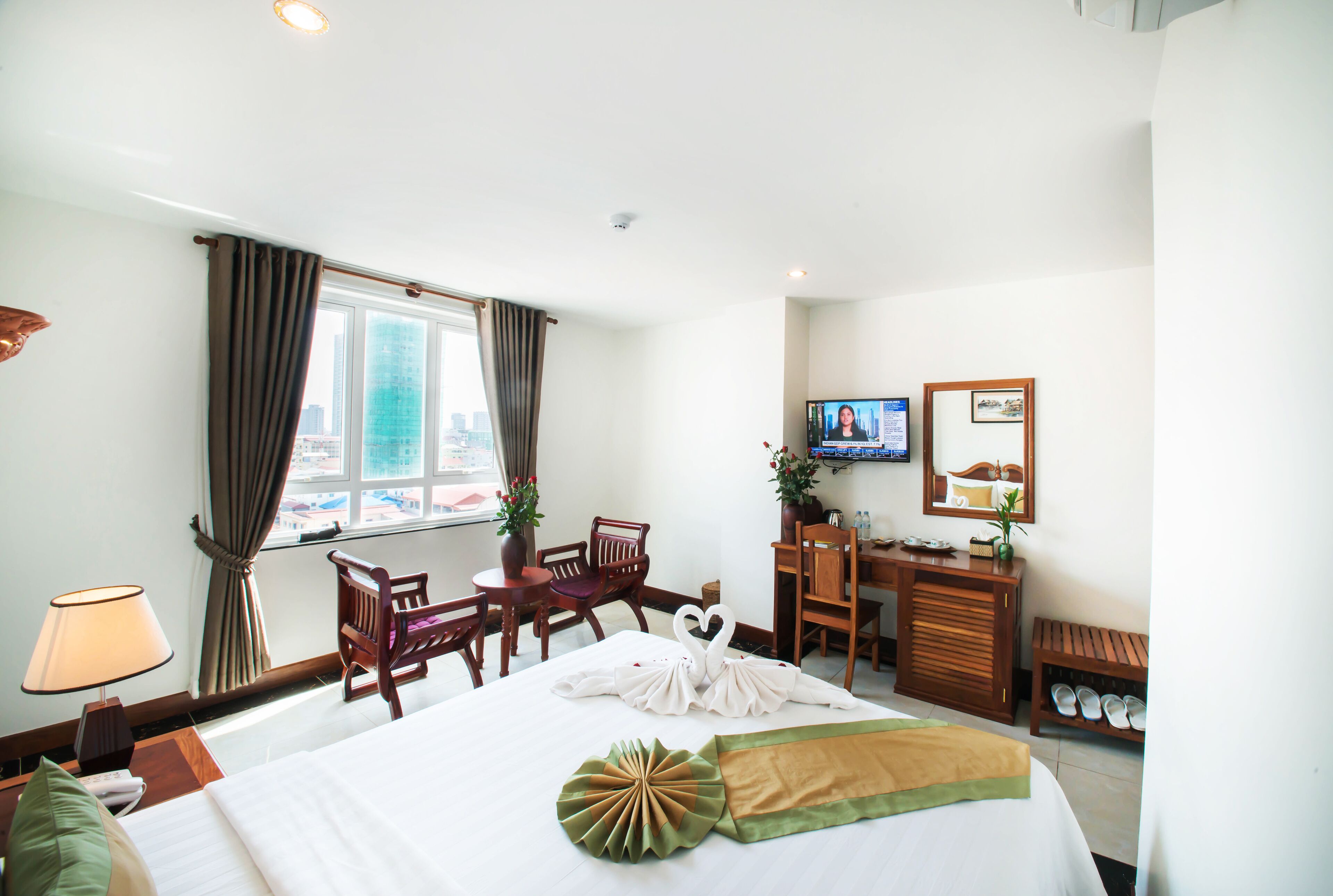 A hotel room with a bed, a desk, a chair, a television, and a window with curtains.