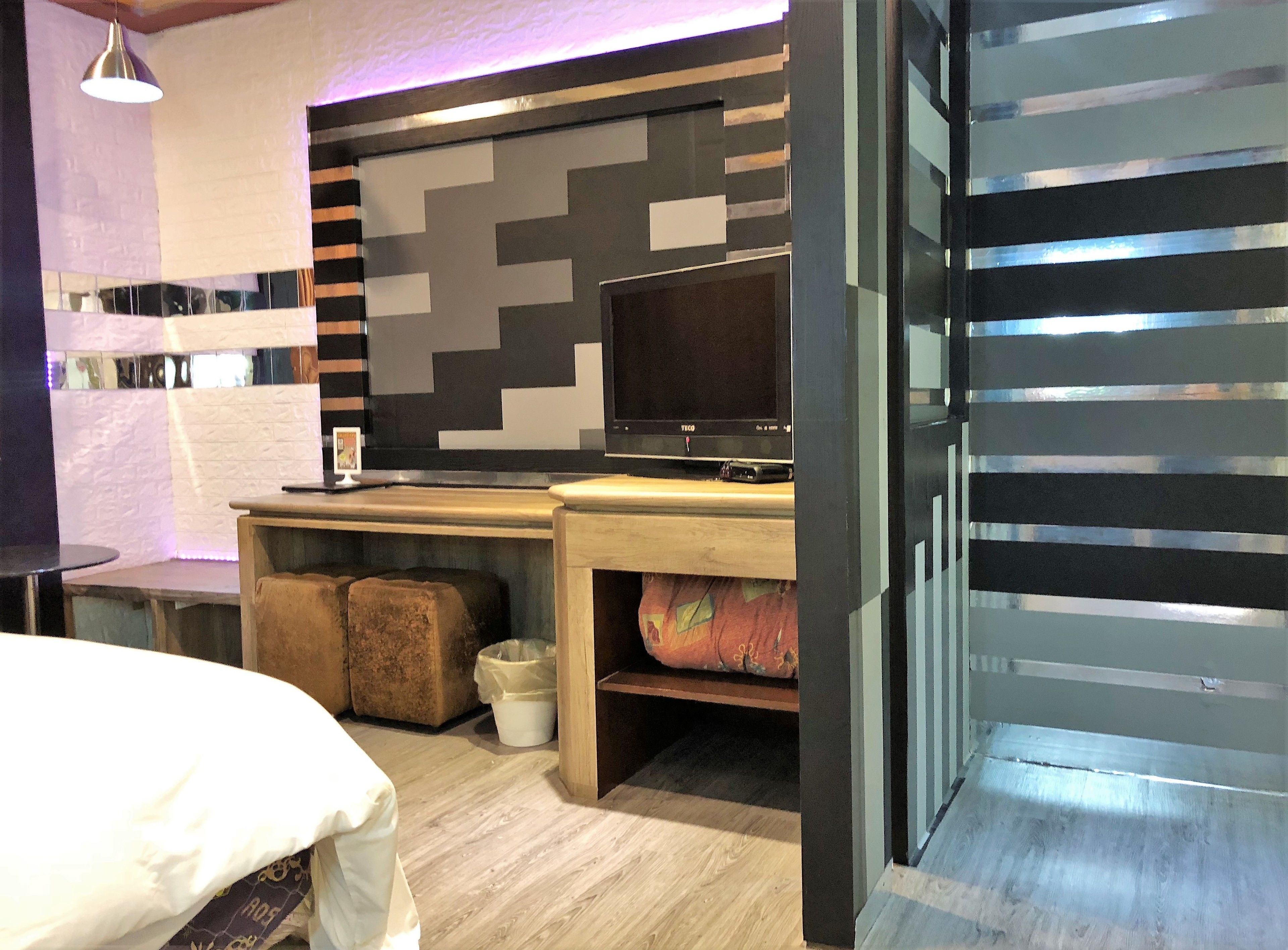 Una habitación moderna con una cama, un escritorio con televisor y una pared con diseño.