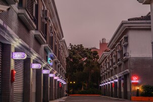 Una hilera de comercios cerrados con letreros iluminados en una calle al anochecer.