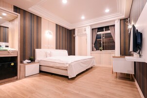 Un dormitorio moderno con una cama grande, mesitas de noche, un armario empotrado, un tocador con espejo y una ventana con cortinas.