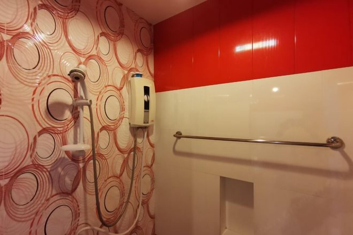 A bathroom with a shower, a hand dryer, and a towel rack.