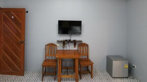 A room with a wooden table and chairs, a flat-screen TV mounted on the wall, and a small heater on the floor. - Happy Field Resort Cha-am (Cha-am)