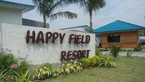 A sign for Happy Field Resort with a white background and brown lettering. - Happy Field Resort Cha-am (Cha-am)