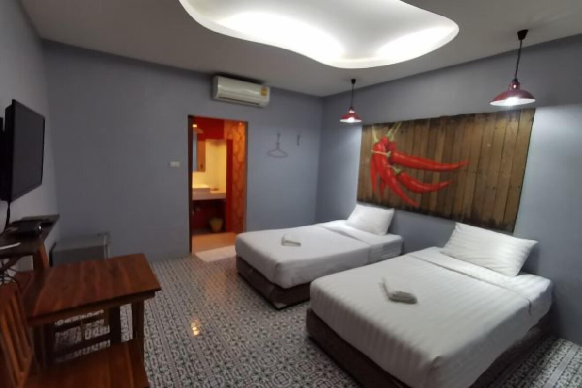 A hotel room with two beds, a desk, a TV, and a large painting on the wall.