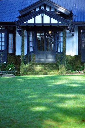 A traditional house with a dark front door, a covered porch, and a well-maintained lawn.
