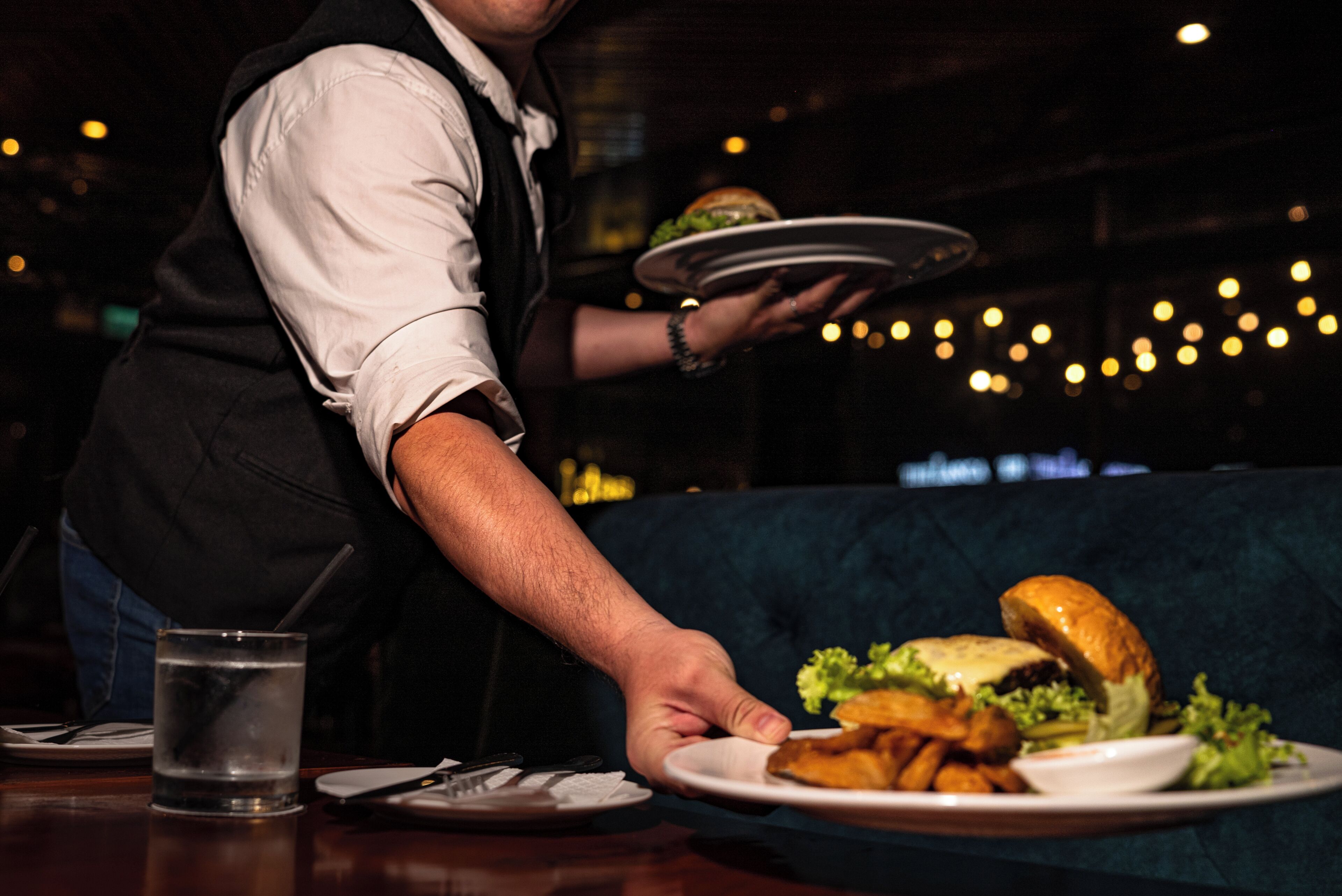Un cameriere serve un hamburger e patatine fritte a un cliente.