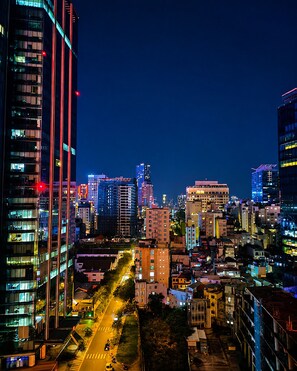Une vue nocturne d’une ville, avec ses gratte-ciel, une rue bien éclairée et une vue dégagée sur le profil urbain.