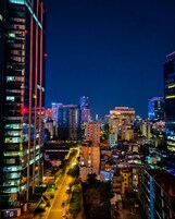 A nighttime cityscape with high-rise buildings, a well-lit street, and a clear view of the urban skyline.