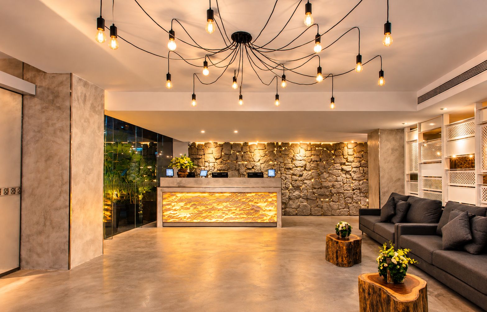 Un vestíbulo moderno con una pared de piedra, un mostrador de recepción y un área de descanso con sofás.