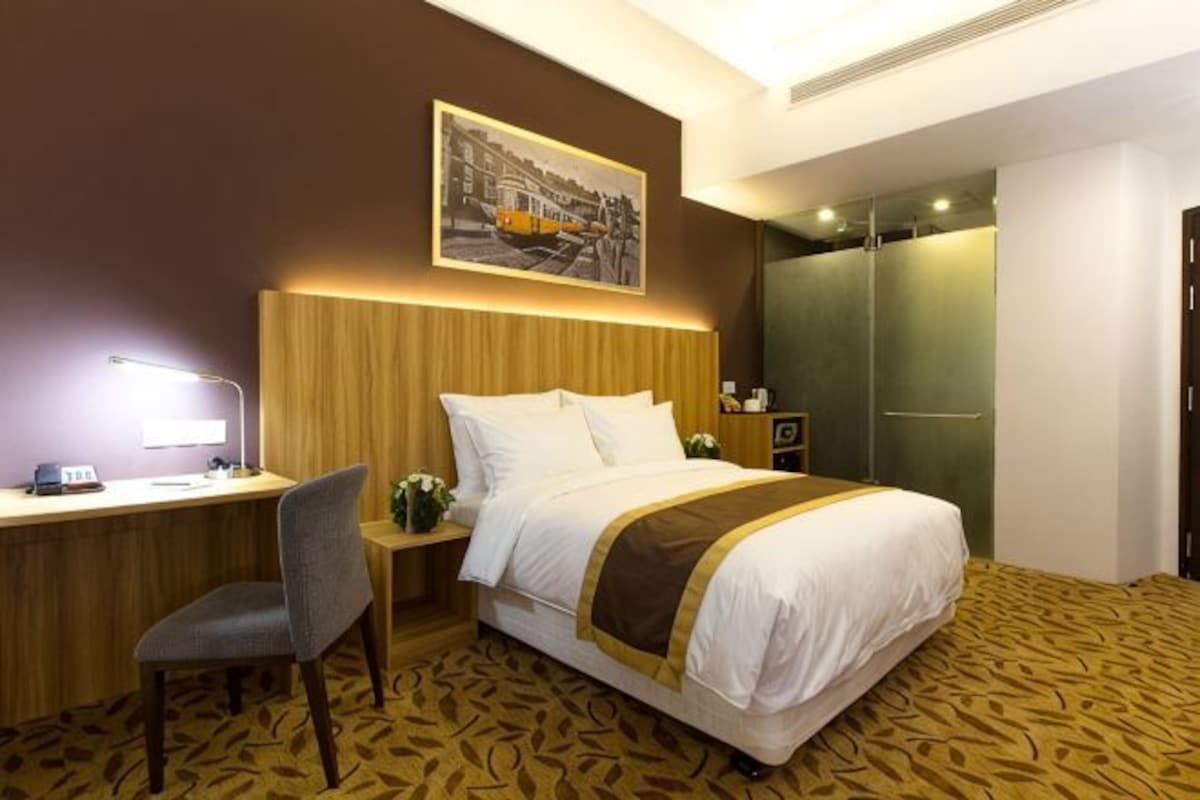 Une chambre d’hôtel avec un lit, un bureau, une chaise et un tableau au mur.