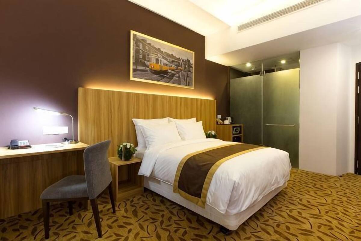 Ein Hotelzimmer mit Bett, Schreibtisch, Stuhl und einem Bild an der Wand.