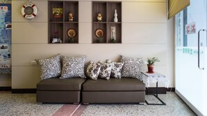 A living room with a sofa, decorative shelves, and a small table with a plant. - Bei Pin B&B (Hengchun)