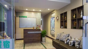 A reception area with a wooden desk, a potted plant, and a sofa with patterned cushions. - Bei Pin B&B (Hengchun)