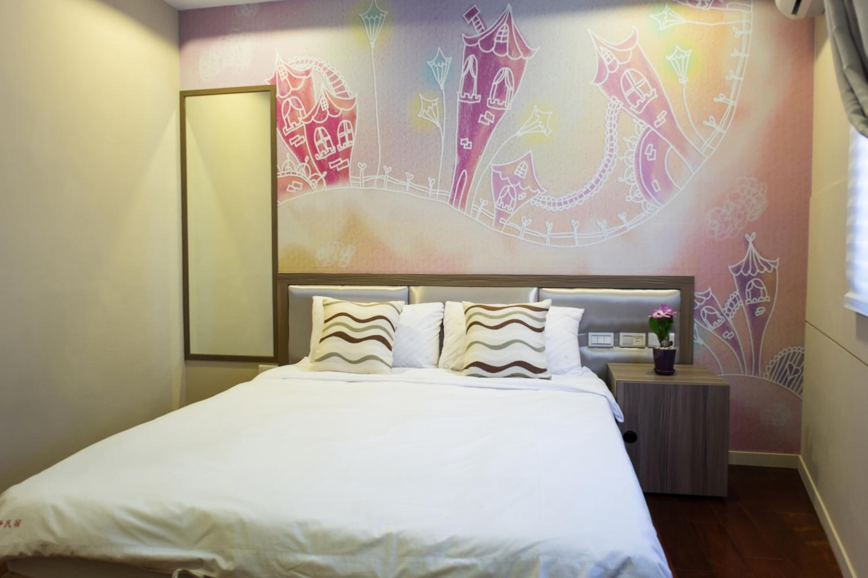 Una habitación de hotel con una cama grande, una mesita de noche y un mural en la pared.