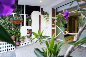 A modern building with a signboard, potted plants, and a glass entrance.