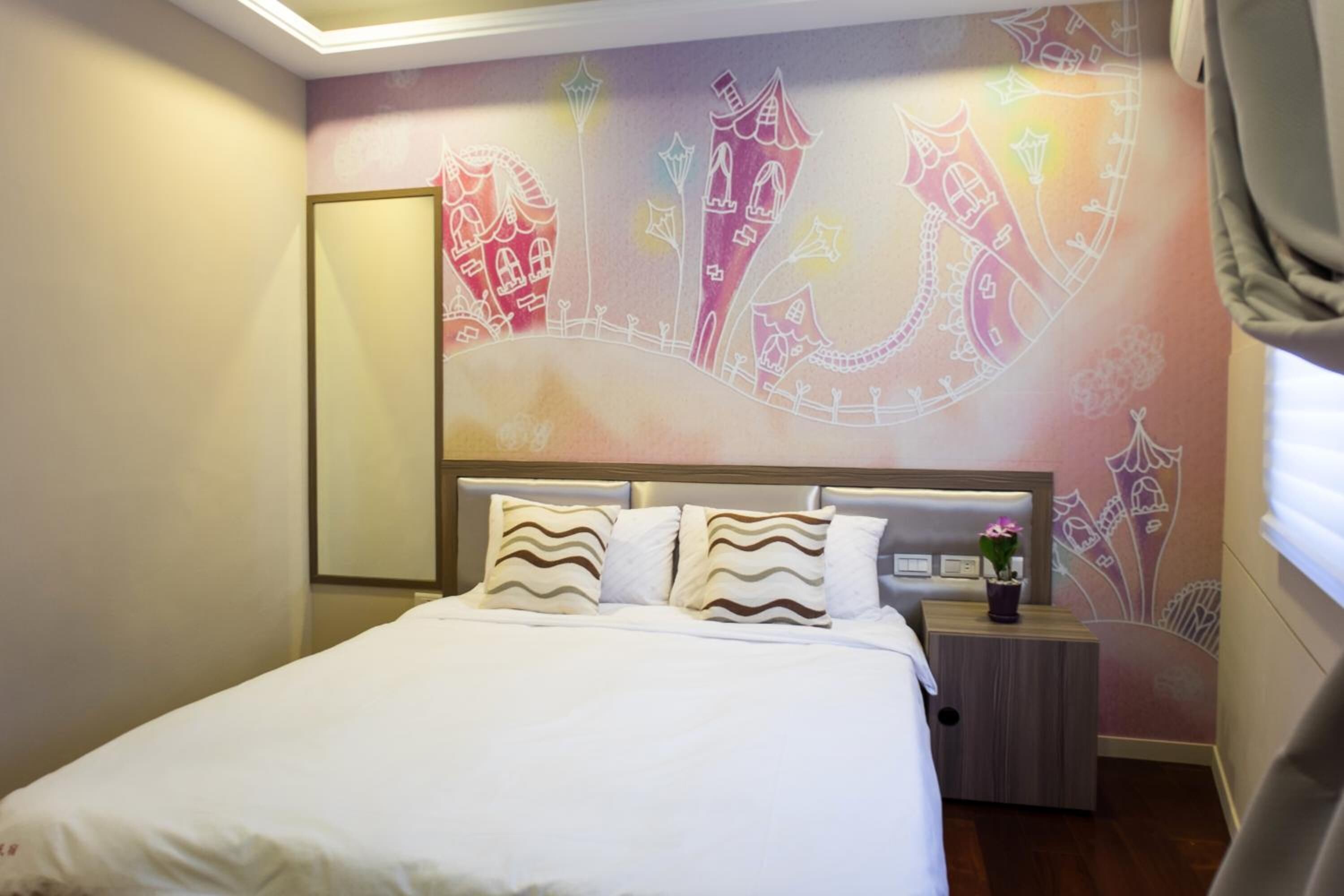 Ein Hotelzimmer mit Bett, Nachttischen und Wandgemälde.