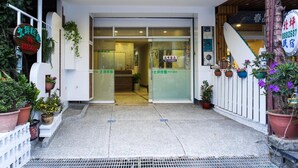 A hotel entrance with a reception desk, potted plants, and a sign indicating the hotel's name. - Bei Pin B&B (Hengchun)