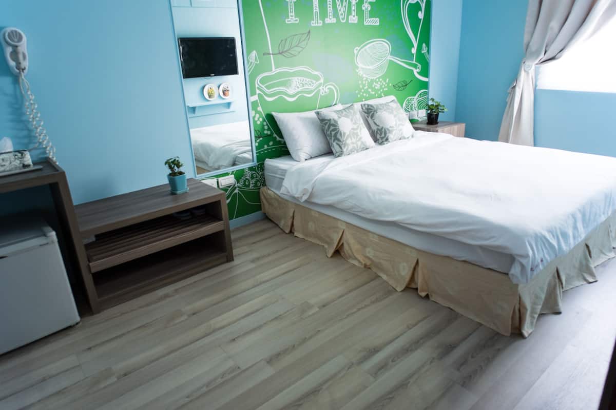 Quarto com cama, mesa de cabeceira, cômoda e parede verde com texto branco.
