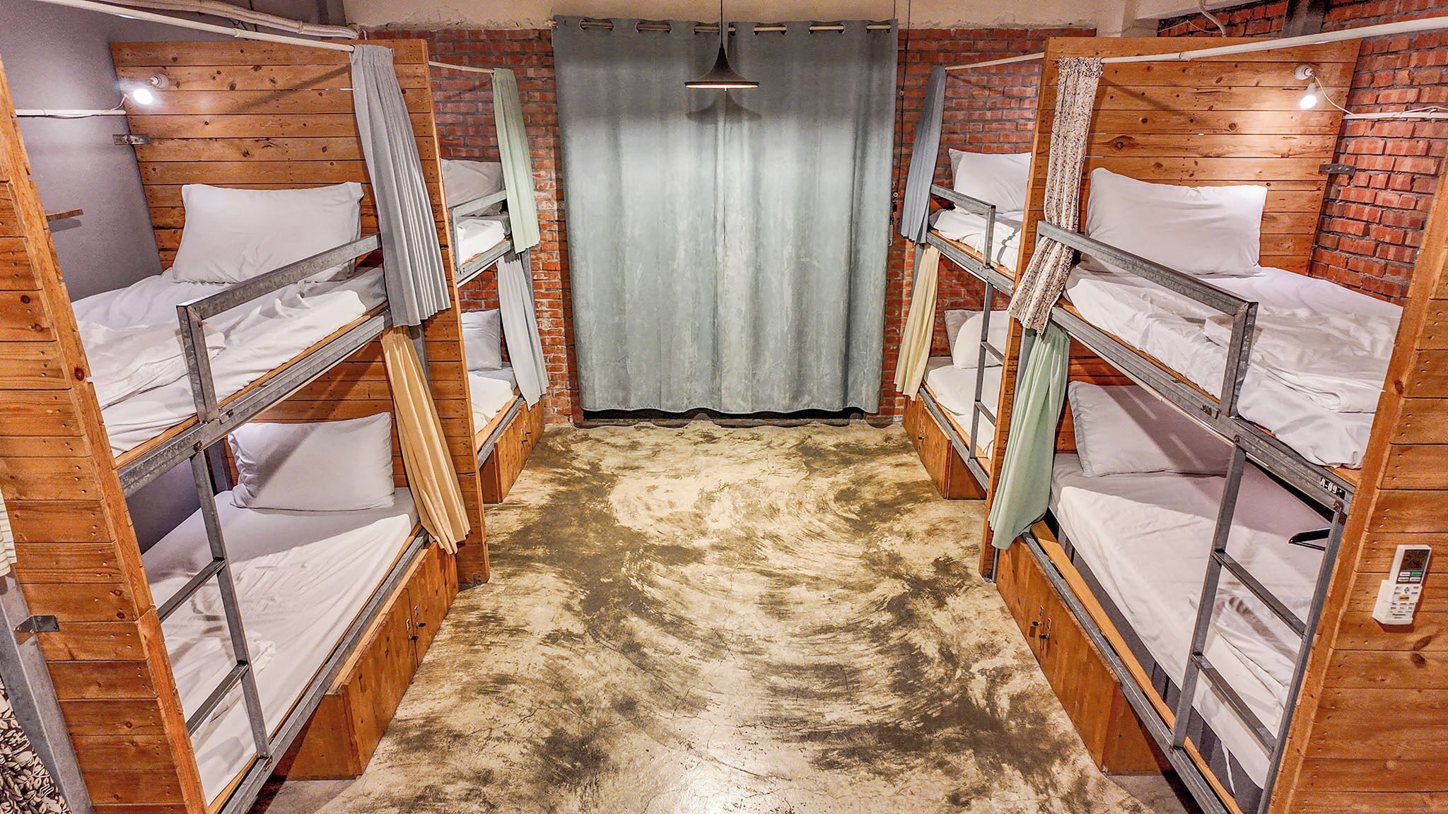 A room with bunk beds arranged in a corridor, wooden walls, and a brick floor.
