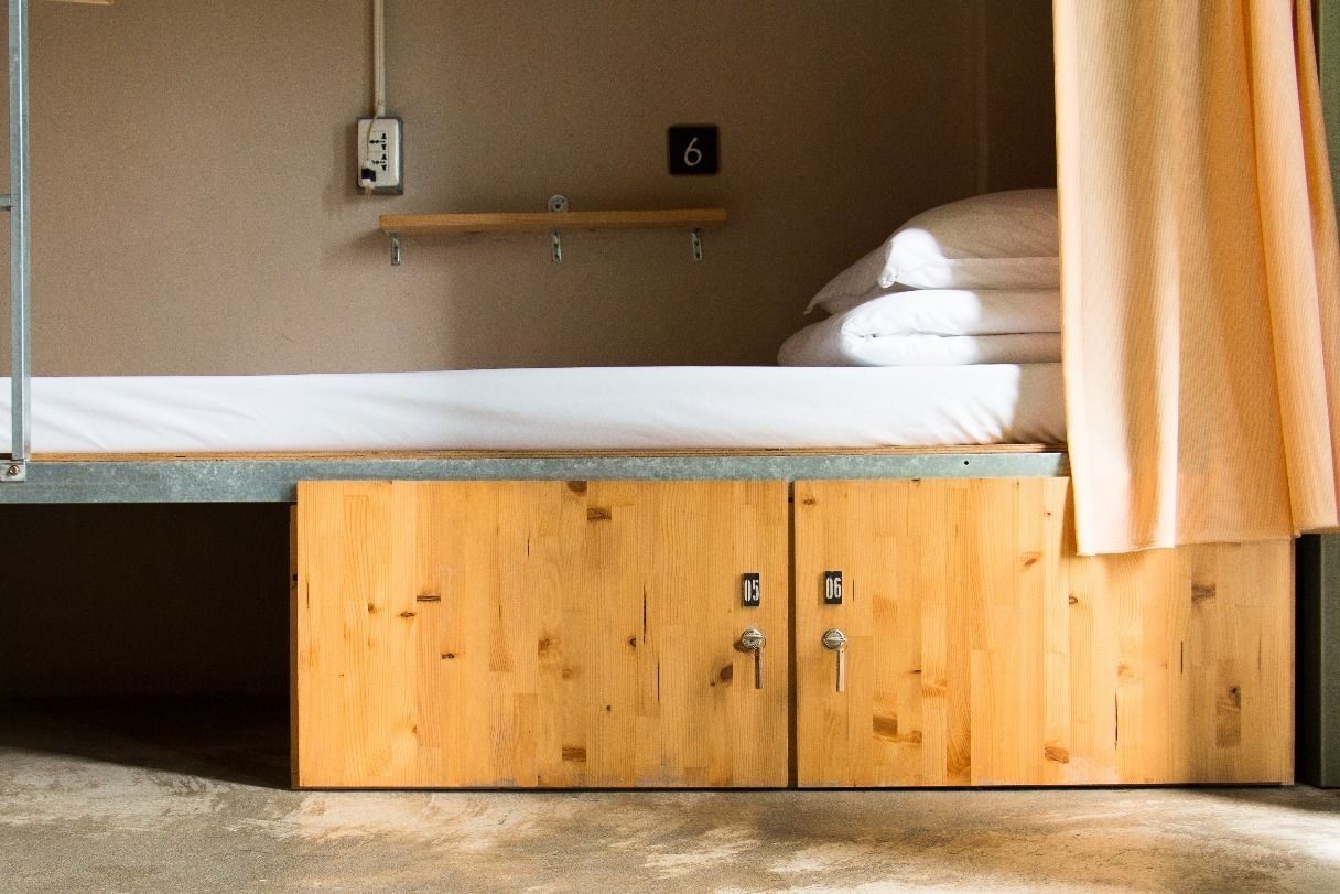 A bunk bed with a wooden cabinet below, a power outlet on the wall, and a number sign.