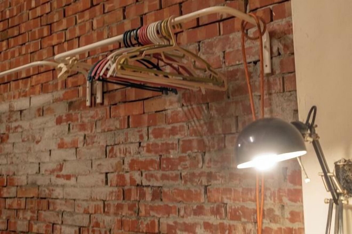 A brick wall with a clothes rack and a lamp.