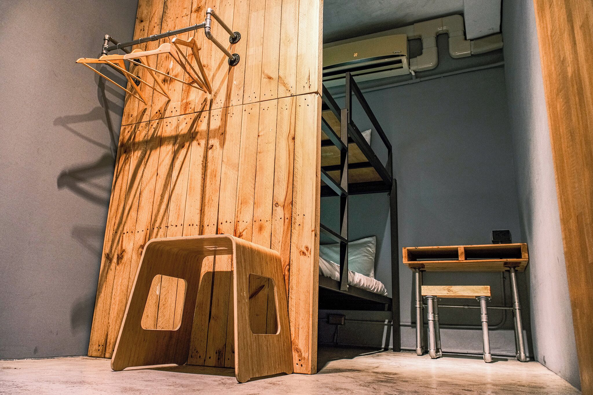 Un letto a castello con una scala in legno e un piccolo sgabello di legno.