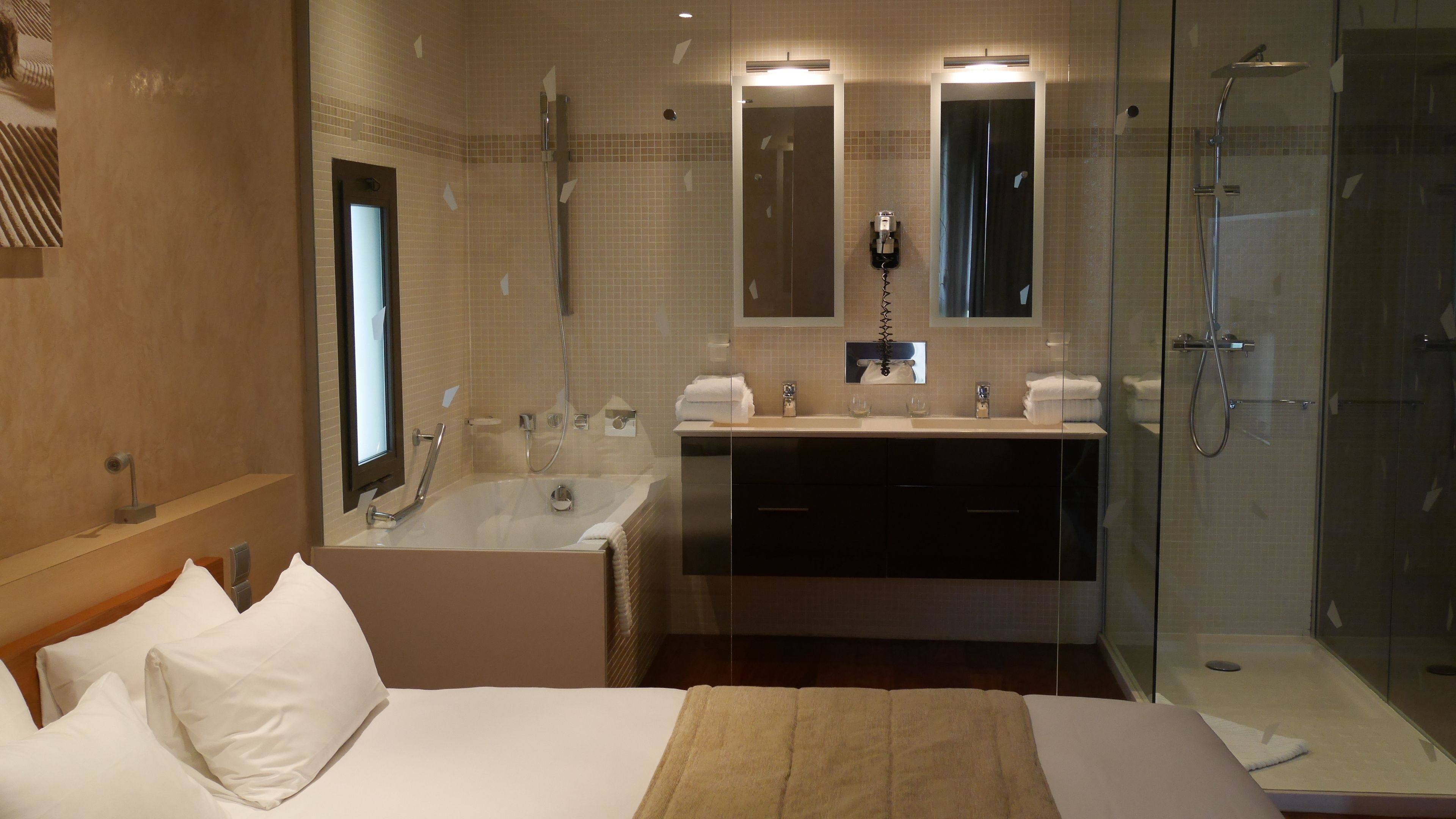Un baño de hotel con una bañera, ducha, lavabo y espejo.