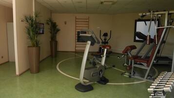 A gym with exercise equipment, a green floor, and potted plants.