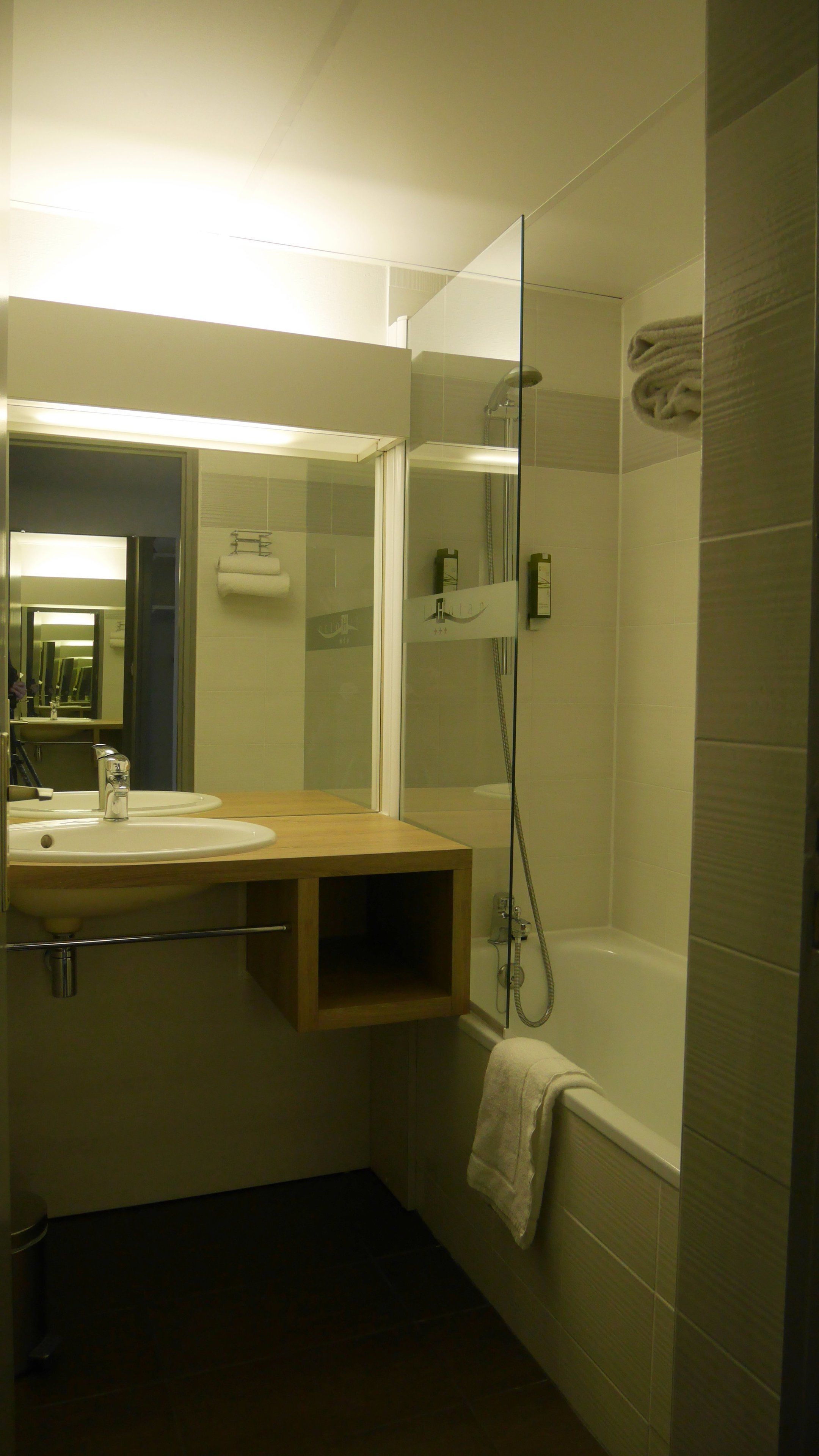 A modern bathroom with a glass-enclosed shower, a sink with a mirror, and a towel hanging on the wall.