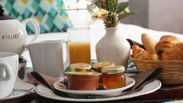 Desayuno con té, café, croissants y miel sobre una mesa.