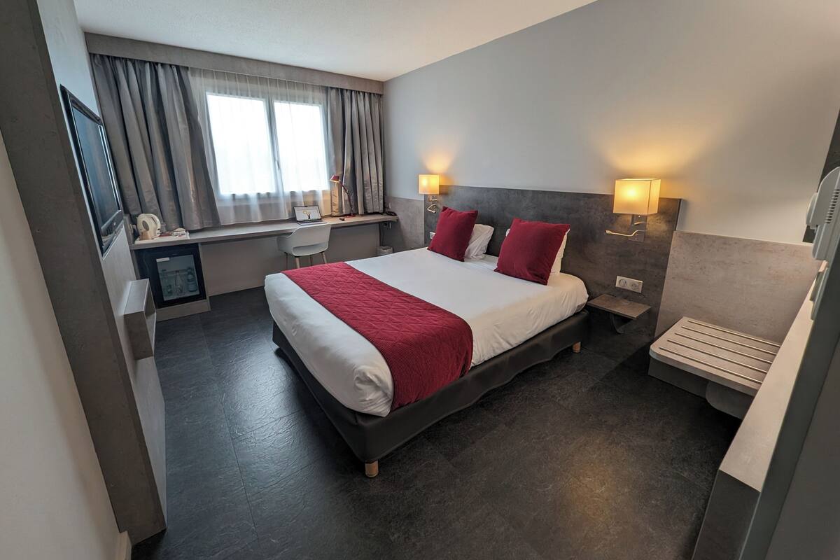 Una habitación de hotel moderna con una cama grande, un escritorio y una silla.