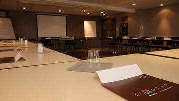 A conference room with tables, chairs, a projector screen, and a presentation screen.