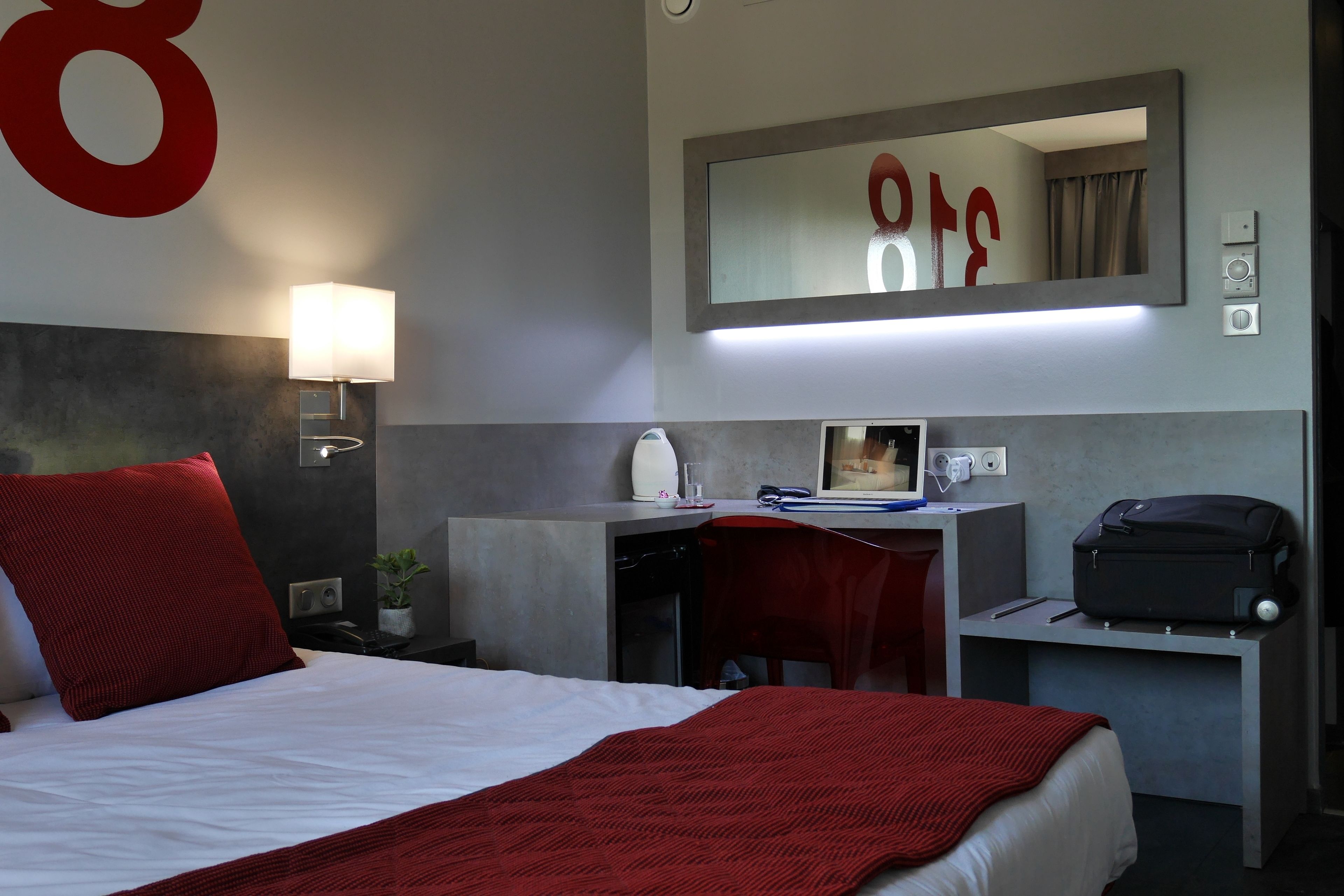 Een hotelkamer met een bed, bureau, stoel en een koffer.
