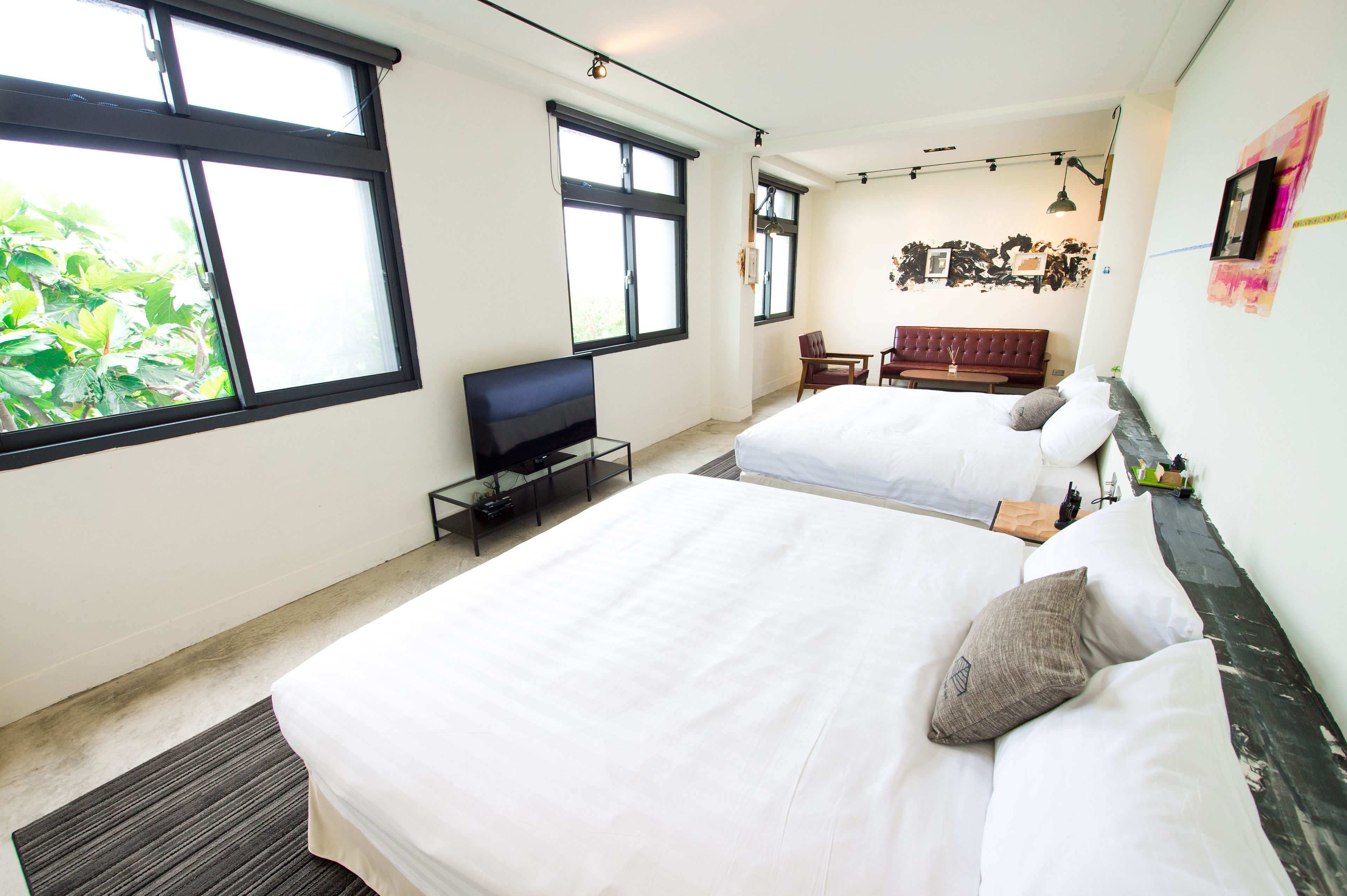 A hotel room with two beds, a TV, a desk, and a couch.
