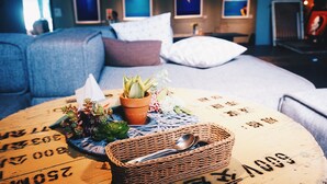 A cozy room with a bed, a round table with a placemat, and a wicker basket. - The Leaf Inn (Hualien City)