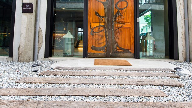 A building entrance with a wooden door, a glass window, and a sign that reads "Leaf Cafe." - The Leaf Inn (Hualien City)