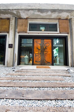 A building entrance with a wooden door, a glass window, and a sign that reads "Leaf Cafe." - The Leaf Inn (Hualien City)