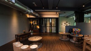 A modern interior with wooden flooring, round tables, and a seating area with cushions. - The Leaf Inn (Hualien City)