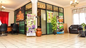 A lobby with a reception desk, black chairs, a large potted plant, and a sign advertising local gems. - Kandy View Hotel (Kandy)