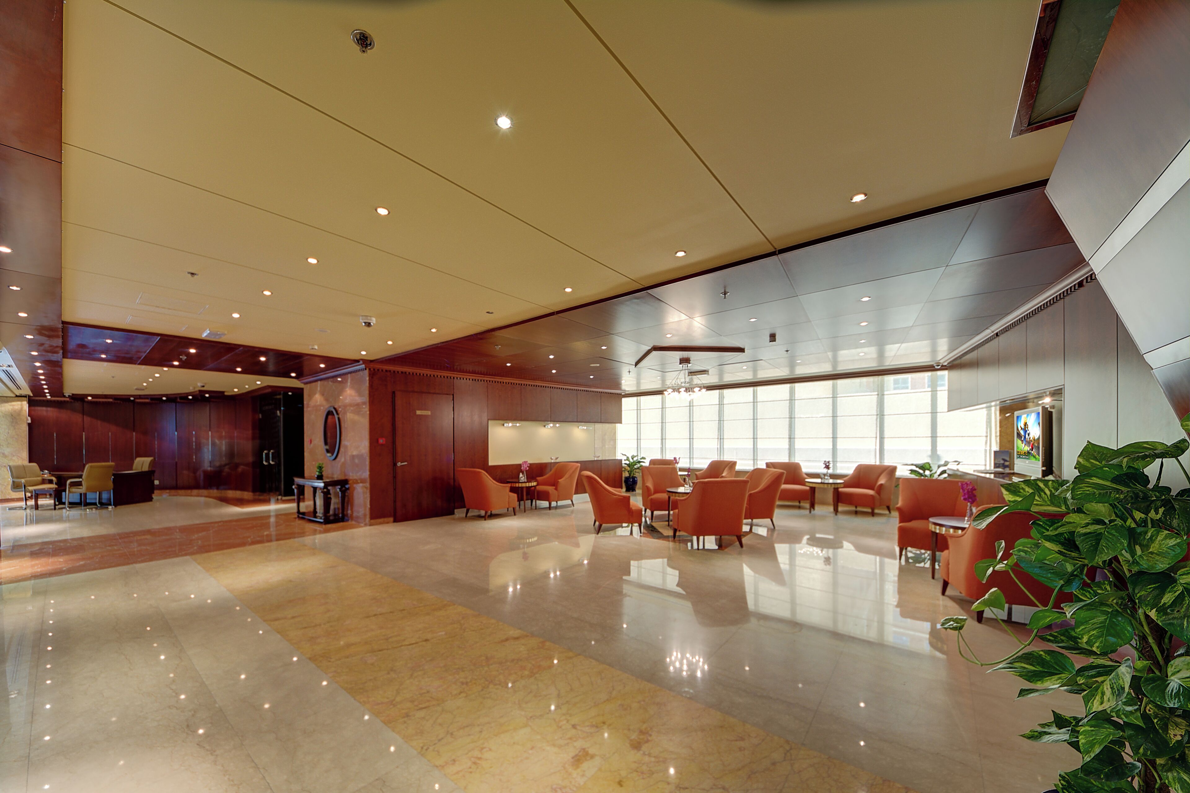 A spacious lobby with a polished marble floor, multiple seating areas, and a large window providing natural light.