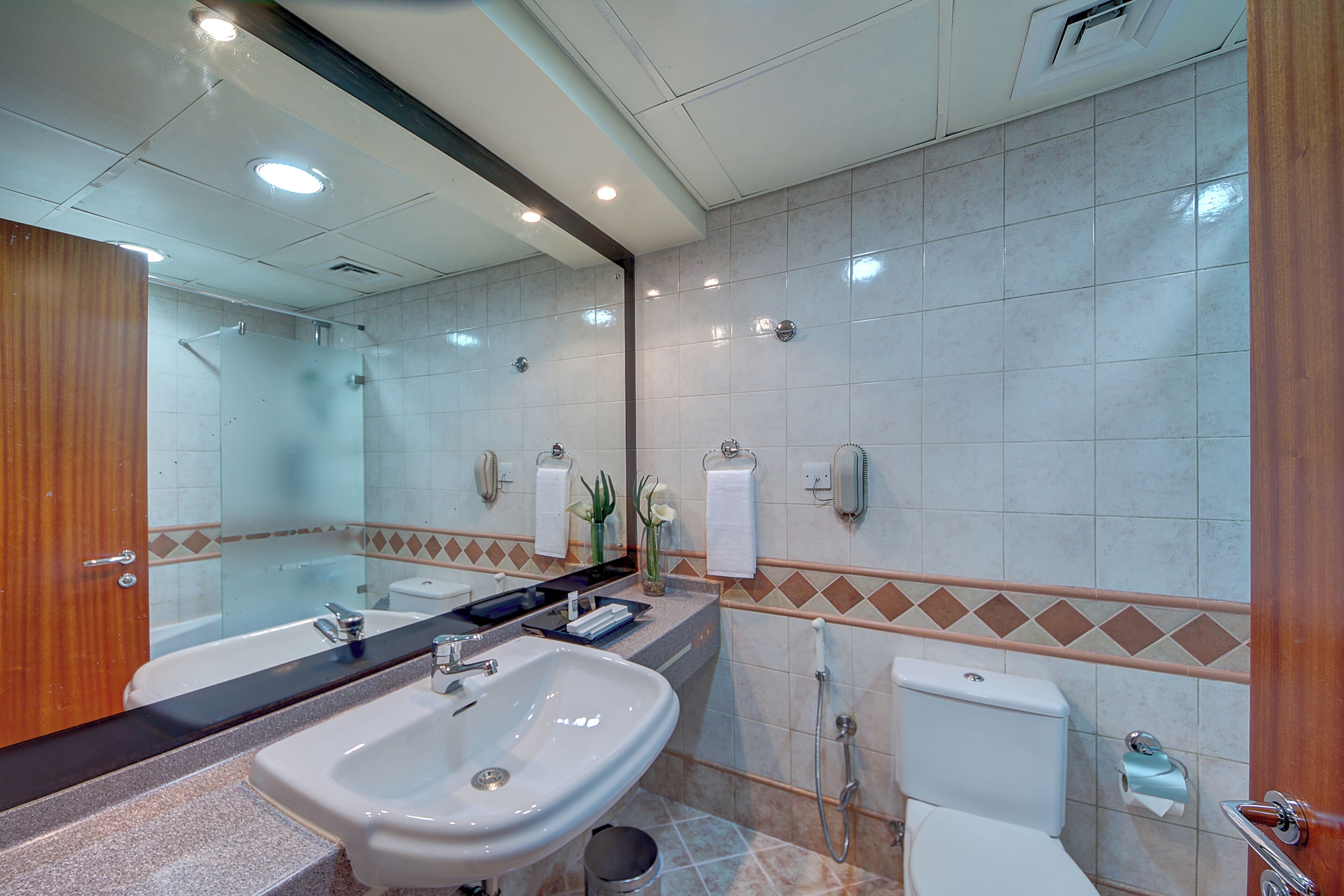 Un bagno moderno con un grande specchio, un lavandino, un water e una doccia.