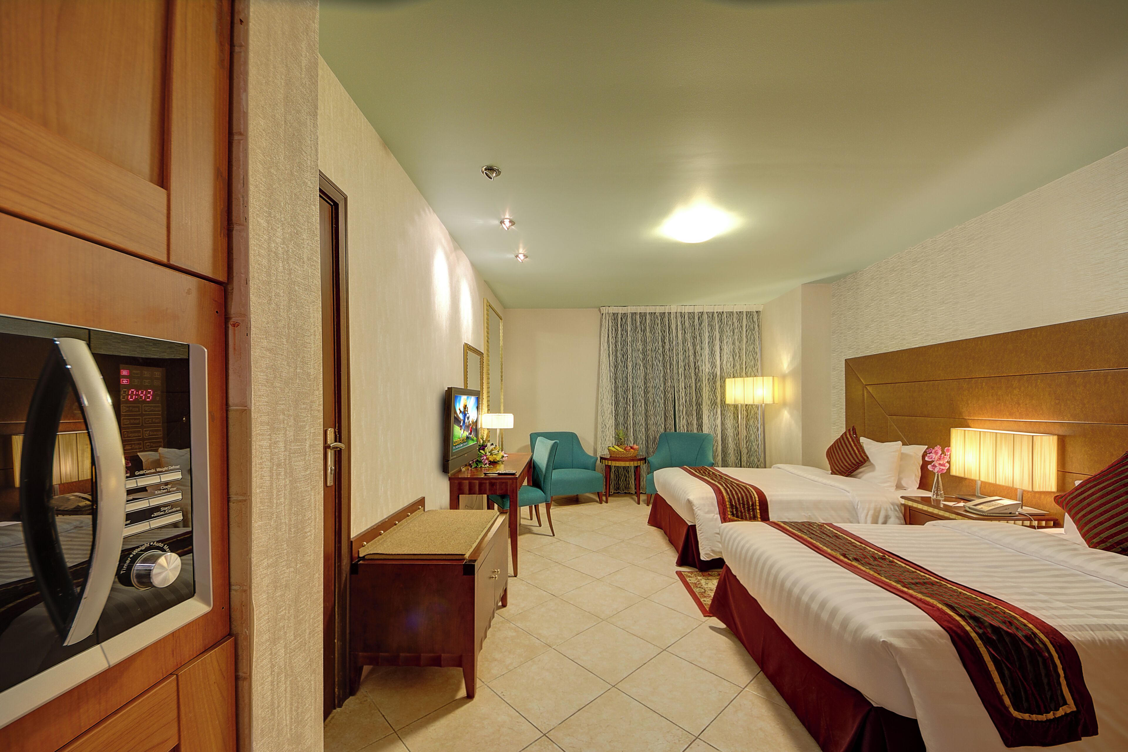 Habitación de hotel con dos camas, un escritorio, televisor, minibar y baño con cortina de ducha.
