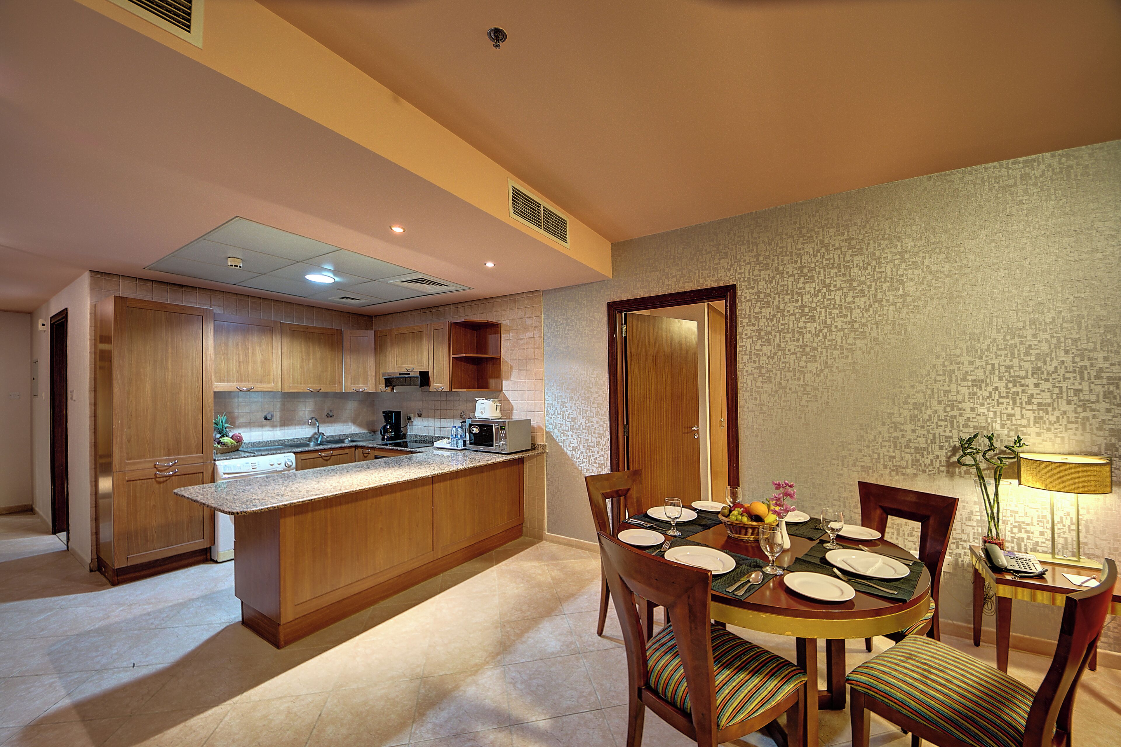 Una cocina moderna con armarios de madera, una mesa de comedor para cuatro personas y una pequeña isla con un microondas.