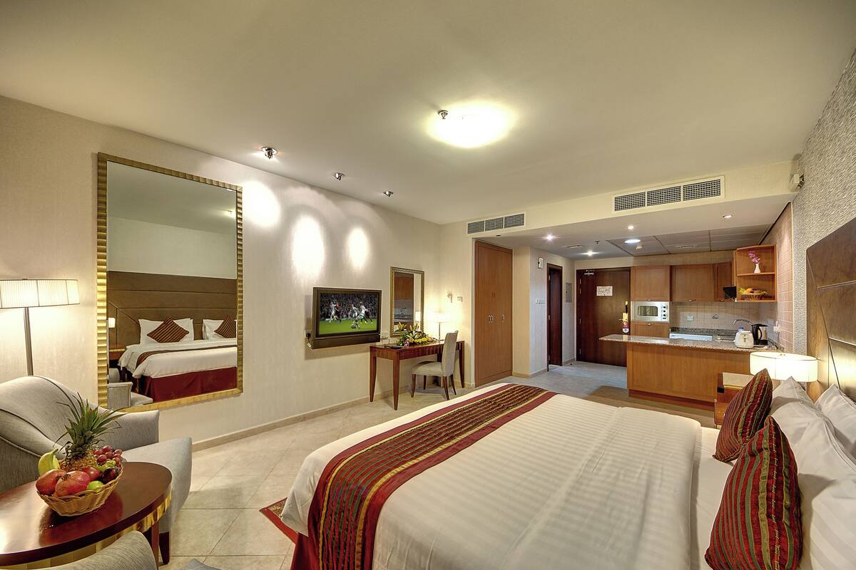 Une chambre d’hôtel équipée d’un grand lit, d’un bureau, d’une chaise, d’une télévision et d’une kitchenette.