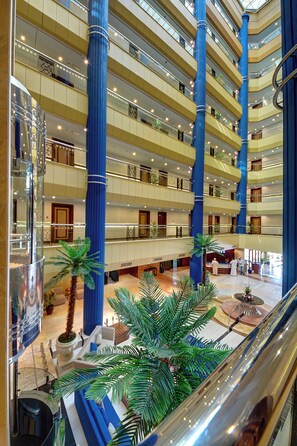 A multi-level hotel atrium with a central column, multiple floors, and a glass ceiling. - Al Manar Grand Hotel Apartments (Dubai)