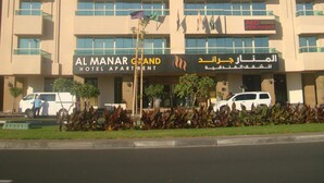 Un hotel de varios pisos con balcones, un cartel que indica tarifas por noche en dirhams de EAU, y señalización en árabe.