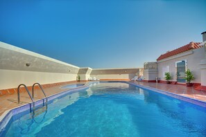 A swimming pool with a tiled edge, a metal ladder, and lounge chairs. - Al Manar Grand Hotel Apartments (Dubai)
